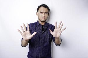gut aussehender asiatischer mann, der blaues hemd mit handgestenhaltung des stopps oder des verbots mit kopienraum trägt foto
