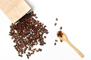 Kaffeebohnen aus Umschlägen und Messlöffel auf weißem Hintergrund