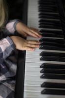 kleines mädchen spielt klavier, kinderhände auf klaviertastatur nahaufnahme, homeschooling, musikalische ausbildung. wachsendes talentiertes kind. tägliche routine für kleinkinder, seitenansicht von kinderhänden und klavier foto