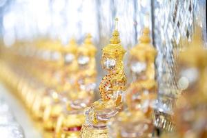transparenter kristallbuddha im goldenen anzug mit unscharfem bokeh glänzendem hintergrund.