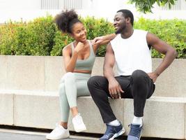 lächelndes junges paar, mann und fröhliche frau, die sich glücklich zusammen im park im freien entspannen. Porträt eines romantischen Mannes, der sorglos mit einer Afro-Haar-Freundin ausgeht. Zwei Personen, Mann und Frau, haben Spaß in der Freizeit. foto