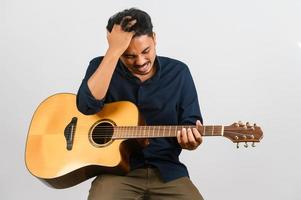 Porträt eines jungen asiatischen Mannes, der eine akustische Gitarre spielt, isoliert auf weißem Hintergrund foto