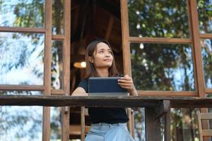 asiatische Frauen sitzen und arbeiten gerne in einem Café. Es gibt grüne Bäume, umgeben von Natur. Unternehmensplanung ist eine gute Idee. foto