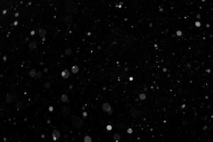 ein Bokeh aus weißem Schnee auf schwarzem Hintergrund foto