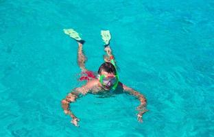Junger Mann, der in klarem, tropischem, türkisfarbenem Wasser schnorchelt foto