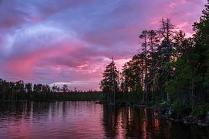 Roter Sonnenuntergang und Sonnenaufgang über Wald und See während der weißen Nächte in Karelien foto