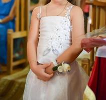Porträt eines jungen Mädchens, das bei der religiösen Hochzeitszeremonie in Weiß gekleidet ist foto