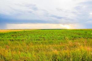 grüne feldlandschaft mit blauem himmel und stürmischen wolken. foto