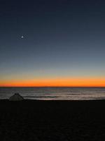 Zelt am Strand bei Sonnenuntergang und Mond foto