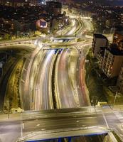 schöne nachtverkehrskreuzungsstraße mit lichtern der fahrzeugbewegungsluftaufnahme von der drohne. vertikale Ansicht foto