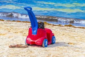 rotes und blaues Spielzeugauto am Strand von Playa del Carmen, Mexiko. foto