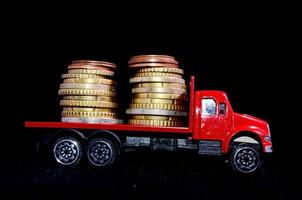 roter Spielzeug-LKW mit Münzen auf schwarzem Hintergrund foto