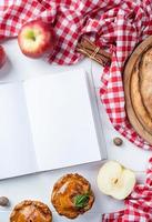 leer geöffnetes kochbuchmodell mit apfelkuchen, fleischkuchen und obst der saison foto