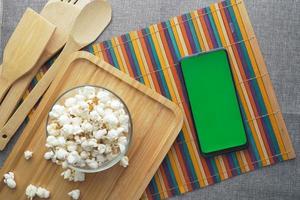 Draufsicht auf Smartphone und Popcorn auf dem Tisch foto