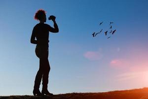 Frau mit Videokamera, die Vögel am Himmel filmt foto