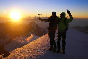 zwei bergsteiger auf dem gipfel des mont blanc bei sonnenaufgang foto