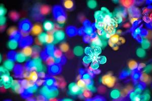 bunte lichter bokeh aus dekorativen leuchtenden blumengirlanden im urlaub, mehrfarbige lichter foto