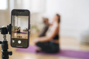 junge Frau mit kleiner Tochter Fitness-Blogger macht Übungen und nimmt Videos auf dem Handy im Studio auf foto