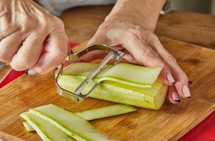 Küchenchef schneidet Zucchini in der heimischen Küche in Scheiben foto