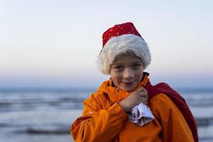 Porträt eines süßen Jungen in einer Kappe von st. Nikolaus, mit einer Tüte Weihnachts- und Neujahrsgeschenke foto