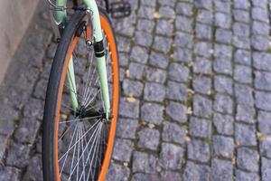 das Rad eines Stadtfahrrads, das an der Wand eines Cafés in der Stadt geparkt ist und mit dem Fahrrad zur Arbeit fährt foto