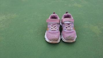 Rosa kleiner Schuh nach dem Training. Nahaufnahme schmutziger Kinderschuhe auf dem Platz. schlammige Turnschuhe für Kinder foto