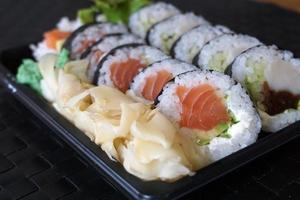 in Scheiben geschnittene Lachsrollen und rohes Thunfisch-Sushi in Plastikbehälter foto