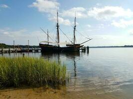 Altes Boot, das am Fluss- oder Seewasser angedockt ist foto