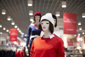 Schaufensterpuppen in einem Bekleidungsgeschäft mit weißer Strickmütze und rotem Pullover. Verkauf von Damenbekleidung. foto