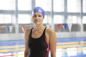 belarus, stadt gomel, 03. september 2021. stadtsportbecken.porträt einer schwimmerin in einem schwimmhut auf dem hintergrund des pools. Frau mittleren Alters im Badeanzug im Pool. foto