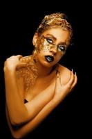 Modekunst goldene Haut. mädchenmodell mit festlichem goldenem glamour brillantem professionellem make-up. kreatives Make-up mit goldener Folie. foto