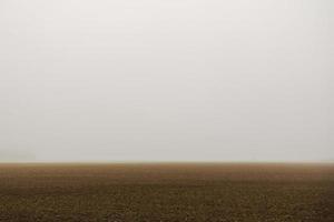 braunes Feld mit sehr dichtem Nebel beim Wandern foto