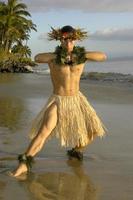 Dieser hawaiianische Hula-Tänzer macht eine Kraftpose und zeigt sein muskulöses Bein am Strand von Maui, Hawaii foto