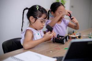 asiatische schüler lernen zu hause, indem sie roboterautos und elektronische platinenkabel in stamm, dampf, mathematik, ingenieurwesen, wissenschaft, technologie, computercode in robotik für kinderkonzepte codieren. foto