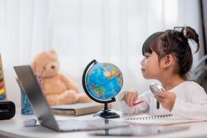 Asiatisches kleines Mädchen lernt das Globusmodell, das Konzept, die Welt zu retten und durch Spielaktivitäten für die Kindererziehung zu Hause zu lernen. foto