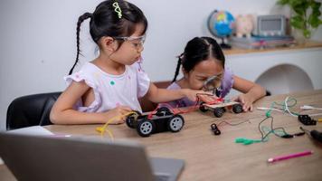 asiatische schüler lernen zu hause, indem sie roboterautos und elektronische platinenkabel in stamm, dampf, mathematik, ingenieurwesen, wissenschaft, technologie, computercode in robotik für kinderkonzepte codieren. foto