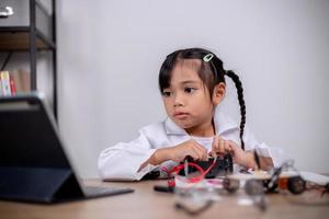 asiatische schüler lernen zu hause, indem sie roboterautos und elektronische platinenkabel in stamm, dampf, mathematik, ingenieurwesen, wissenschaft, technologie, computercode in robotik für kinderkonzepte codieren. foto