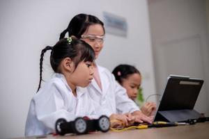 asiatische schüler lernen zu hause, indem sie roboterautos und elektronische platinenkabel in stamm, dampf, mathematik, ingenieurwesen, wissenschaft, technologie, computercode in robotik für kinderkonzepte codieren. foto