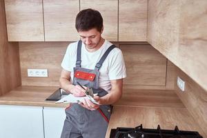 Klempner unterzeichnet einen Vertrag für die Dienstleistungen in der Küche foto