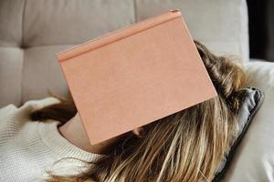 Frau schläft auf Couch mit Buch foto