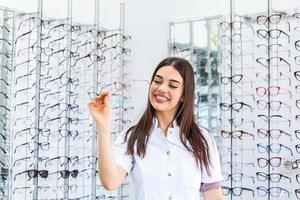 attraktive junge Ärztin in der Augenklinik. augenarzt steht in der nähe von regalen mit brillen. foto