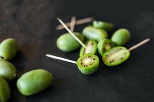 neuseeländisches exotisches essen. Beeren-Nergi oder kleine Kiwi. grauer Steinhintergrund. Baby-Kiwi oder Mini-Kiwi-Früchte auf Steinhintergrund. Nahaufnahme foto