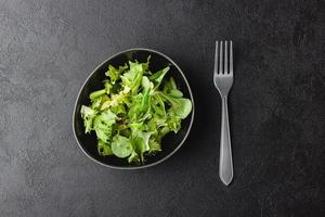 grüne salatblätter in schüssel auf schwarzem tisch. foto