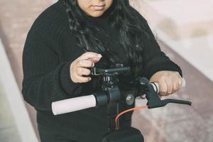 Nahaufnahme einer jungen Latina-Frau, die mit einer Smartphone-Anwendung einen Elektroroller fährt foto