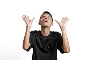 überraschter asiatischer mann im schwarzen trainingst-shirt, der klaffend über den kopierraum schaut. durch weißen Hintergrund isoliert foto