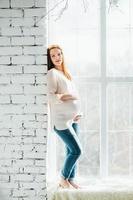 rothaariges schwangeres Mädchen in einer hellen Bluse und Blue Jeans foto