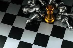 erfolgreich. goldenes königsschach mit silbernen schachfiguren auf schachbrettspielwettbewerb auf dunklem hintergrund, schachkampf, erfolg, teamleiter, sieg, teamarbeit und geschäftsstrategiekonzept foto