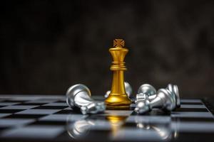 Teamleiter. goldener könig umgeben von silbernen schachfiguren auf schachbrettspielwettbewerb mit kopierraum auf dunklem hintergrund, schachkampf, erfolg, teamleiter, teamarbeit, geschäftsstrategiekonzept