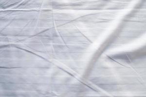 weiße bettwäscheverlaufsstruktur verschwommener kurvenstil aus abstraktem luxusstoff, zerknitterter bettwäsche und dunkelgrauen schatten, hintergrund foto