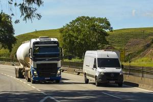 rio, brasilien - 17. oktober 2023, präsidenten-dutra-autobahn, die einen lkw und einen kleinen frachtwagen zeigt, der sich auf der straße bewegt foto